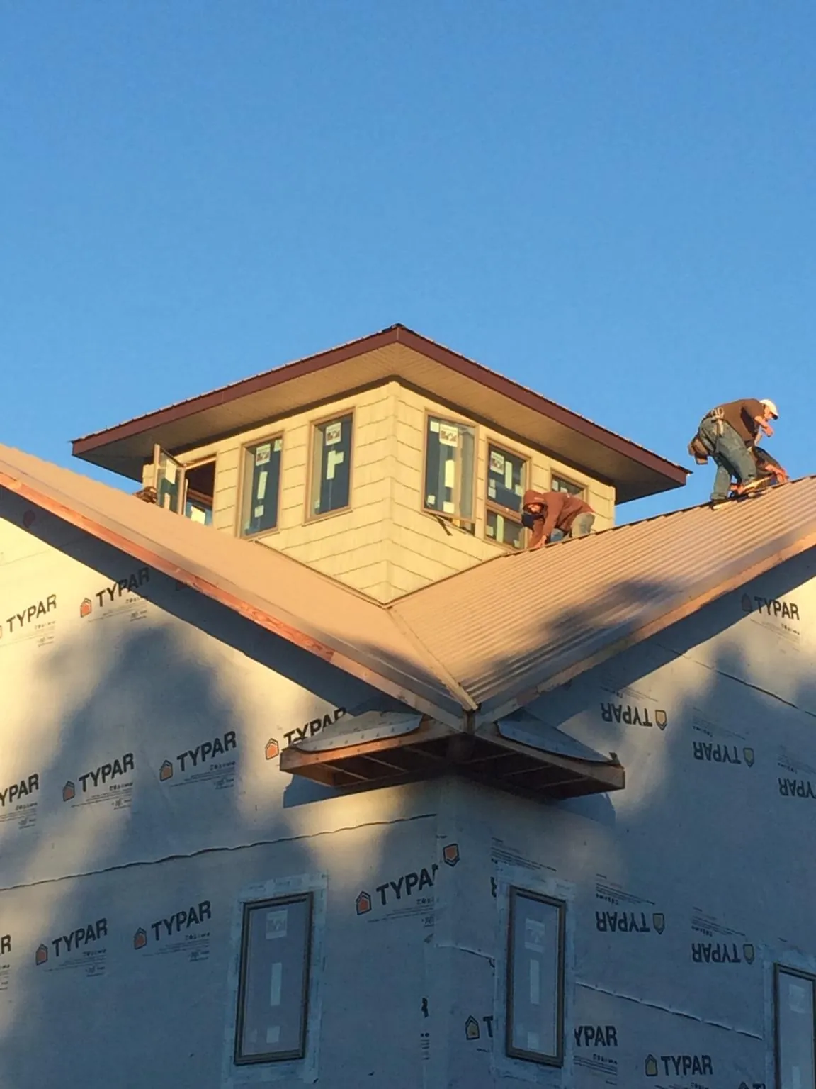 Roofers working around a rooftop cupola on a new metal roof at sunset — Roof Waterproofing in Buxton by Roofing Brothers